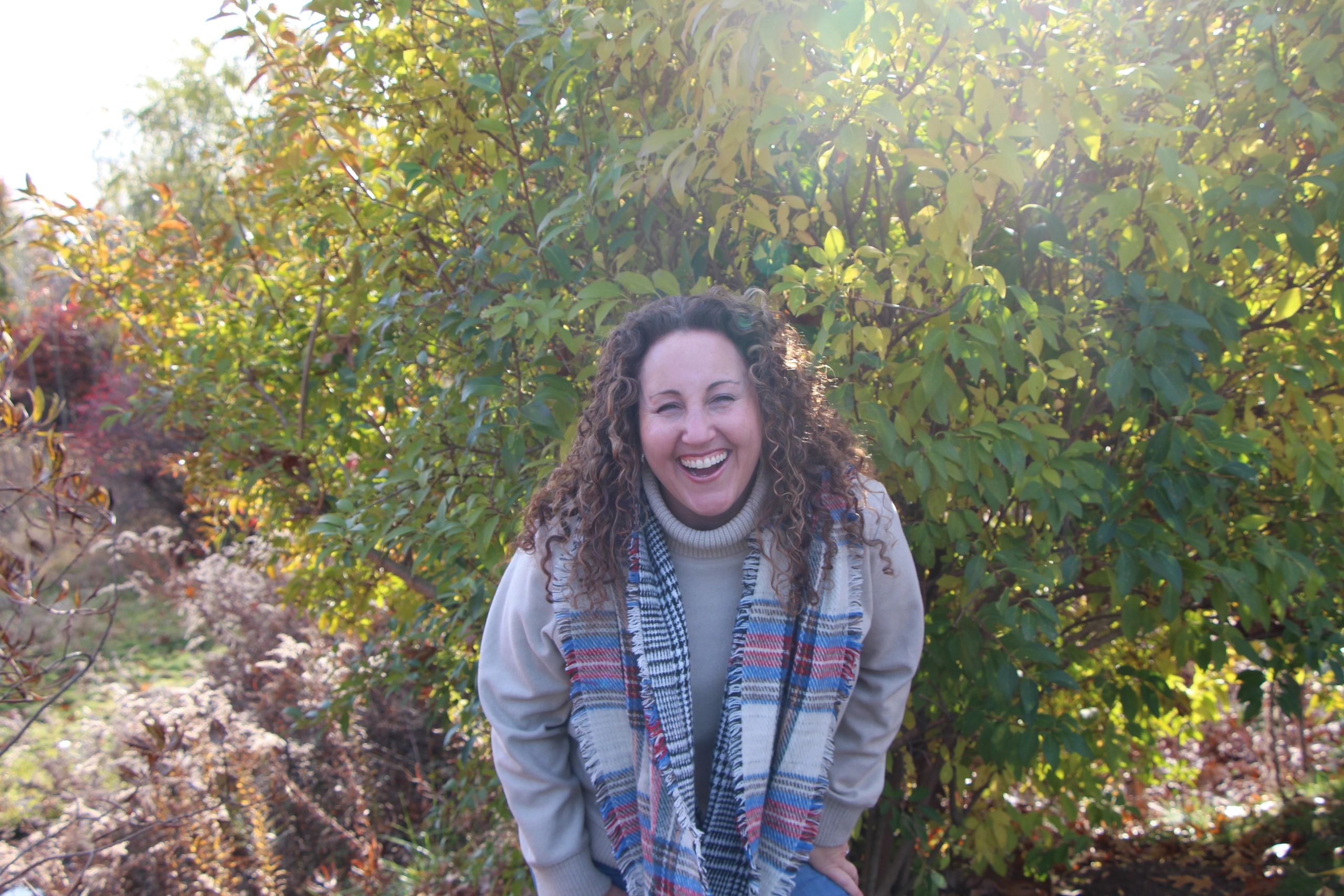A joyful woman laughing outdoors in autumn.