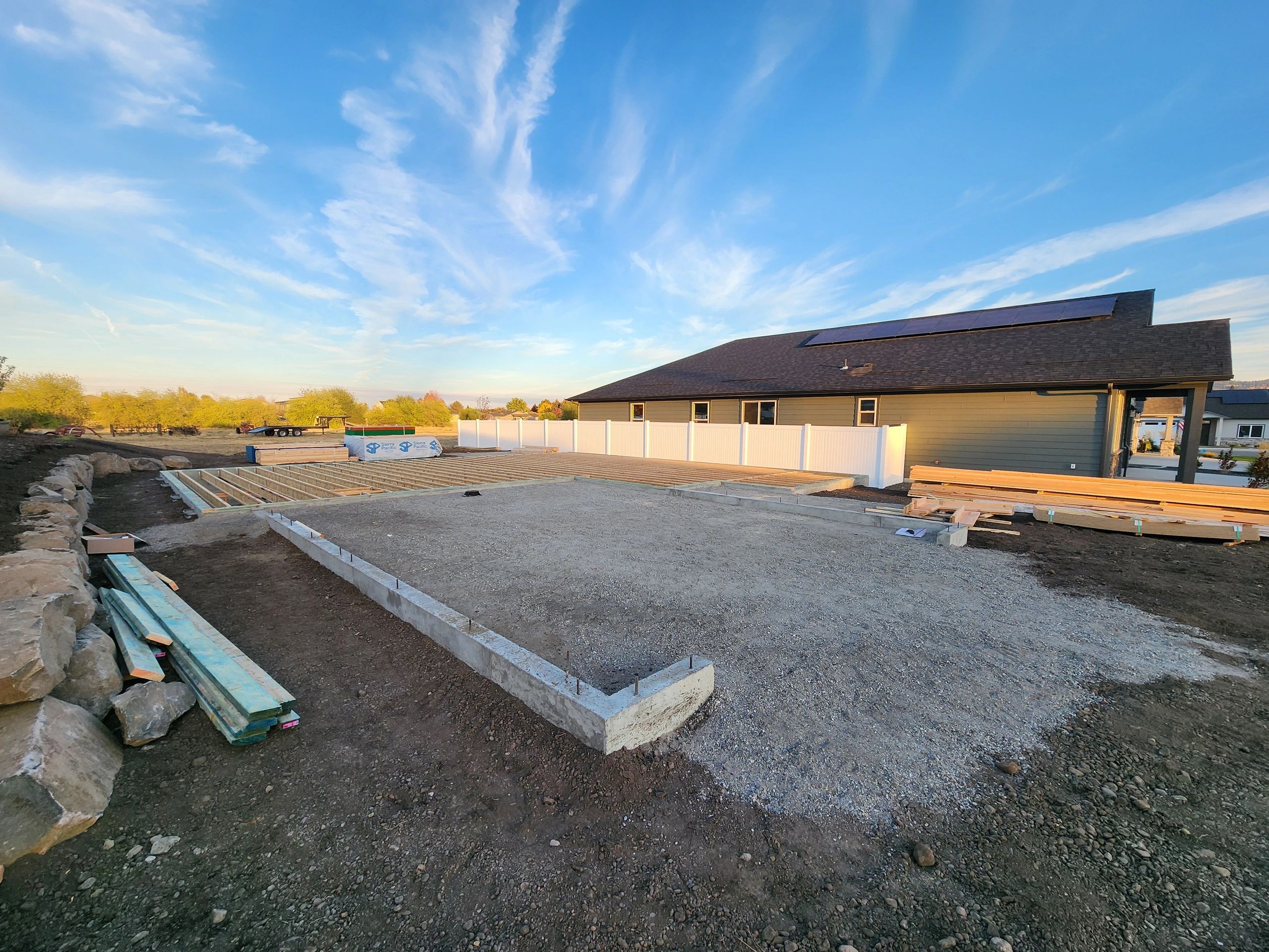 Construction site with foundation and wood framing next to a house.