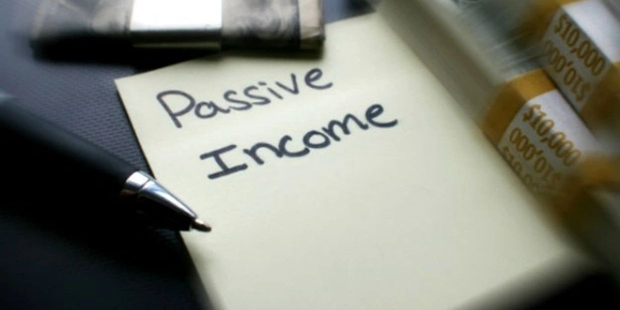 Pen and sticky note with 'Passive Income' written on a desk with money nearby.