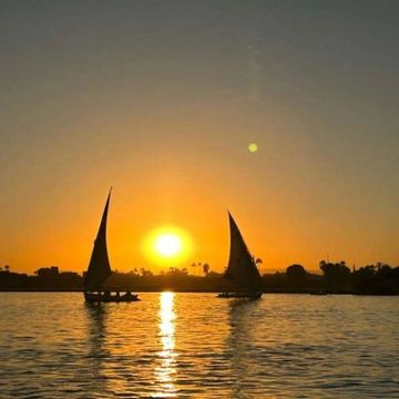 Traditional felucca sailing on the Nile River in Cairo during a beautiful sunset


