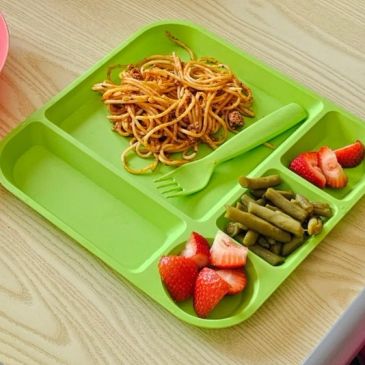 Meal tray with spaghetti, green beans, and strawberries.
