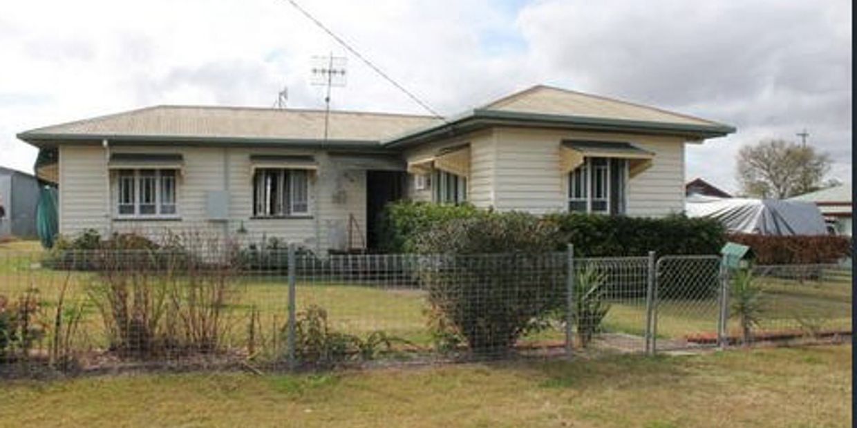 Single-story suburban house with a fenced front yard and garden.