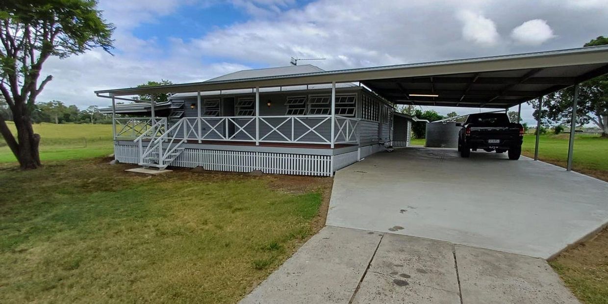 A countryside house with a covered carport and a black pickup truck.