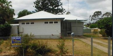 Single-story house with a white exterior and a for sale sign in front.