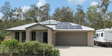 Modern house with solar panels and a driveway with a parked camper.