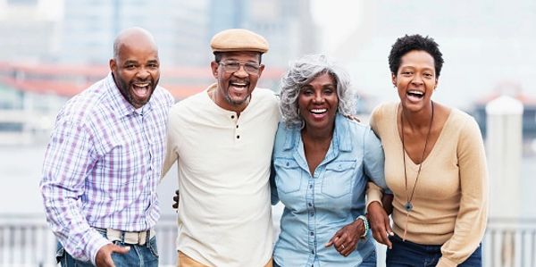 Four joyful adults smiling outdoors.