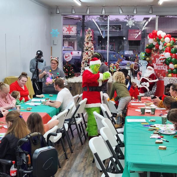 A person dressed as the Grinch interacts with children at a festive Christmas event.