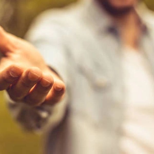 A person extending their hand forward in a gesture of offering or help.