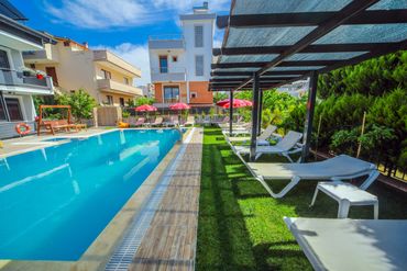 Outdoor pool area with sun loungers and umbrellas on a sunny day.