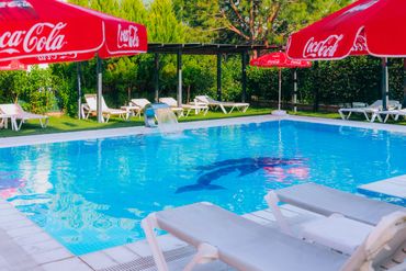 Outdoor pool with Coca-Cola umbrellas and lounge chairs on a sunny day.