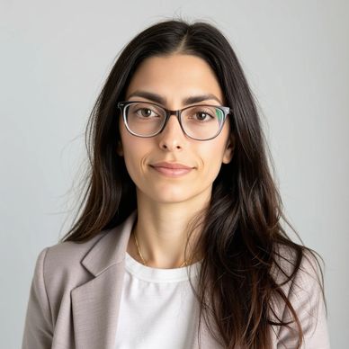 Portrait of a woman with glasses and long dark hair wearing a blazer.