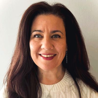 Smiling woman with long dark hair and a white sweater.