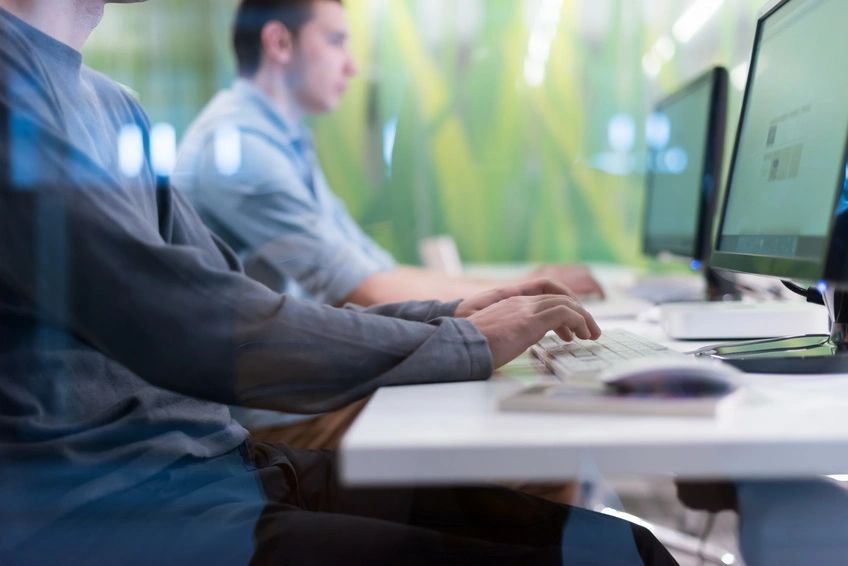 Two people working on computers in an office.