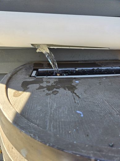 Water flowing from a pipe onto a surface below.
