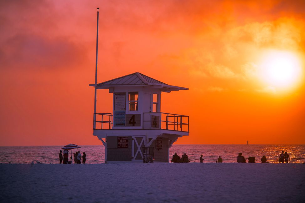 Clearwater beach Florida sunset over looking beach with small waves and people sitting watching 