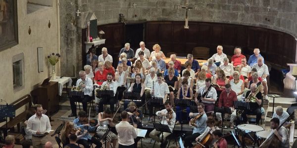 Orchestra and choir performing inside a historic church with stone walls and wooden panels.