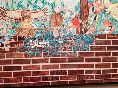 Colorful mural of various birds perched on a branch against a brick wall.