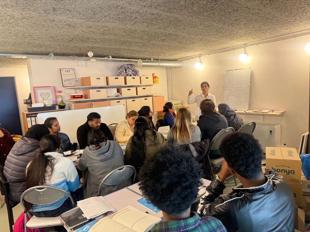 A diverse group attends a classroom session led by a teacher in a cozy room.