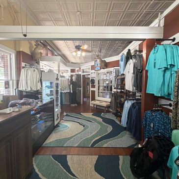 Interior of a clothing store with casual wear and patterned rug.
