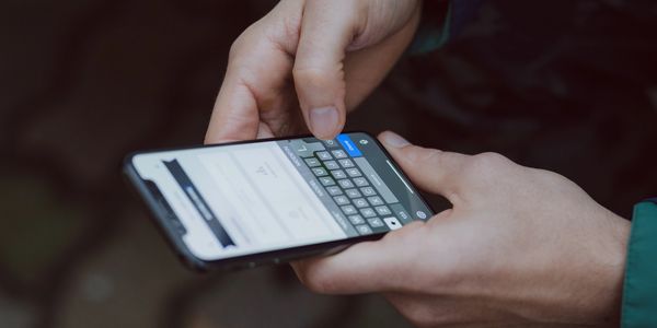 Person's hands holding a mobile phone and starting to type an email