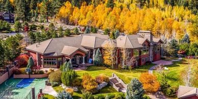 Large house surrounded by autumn trees.