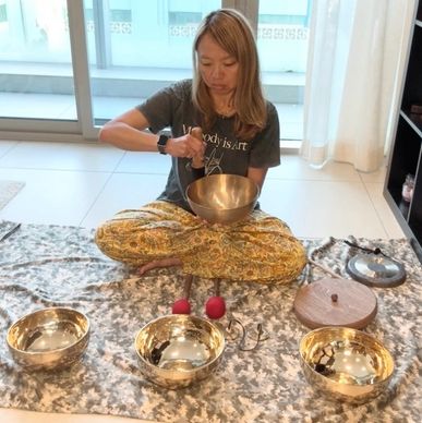 Woman playing singing bowls in a calm indoor setting.