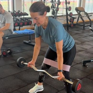 Woman lifting weights with resistance band in gym.