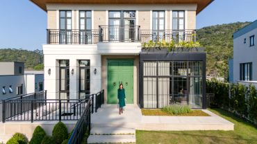 Casa moderna com porta verde e mulher na entrada.