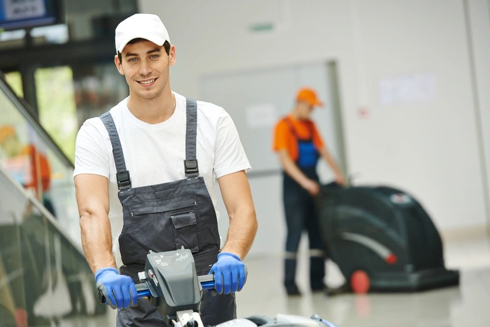 Cleaner male man workers with mop in uniform cleaning corridor pass or hall floor of building