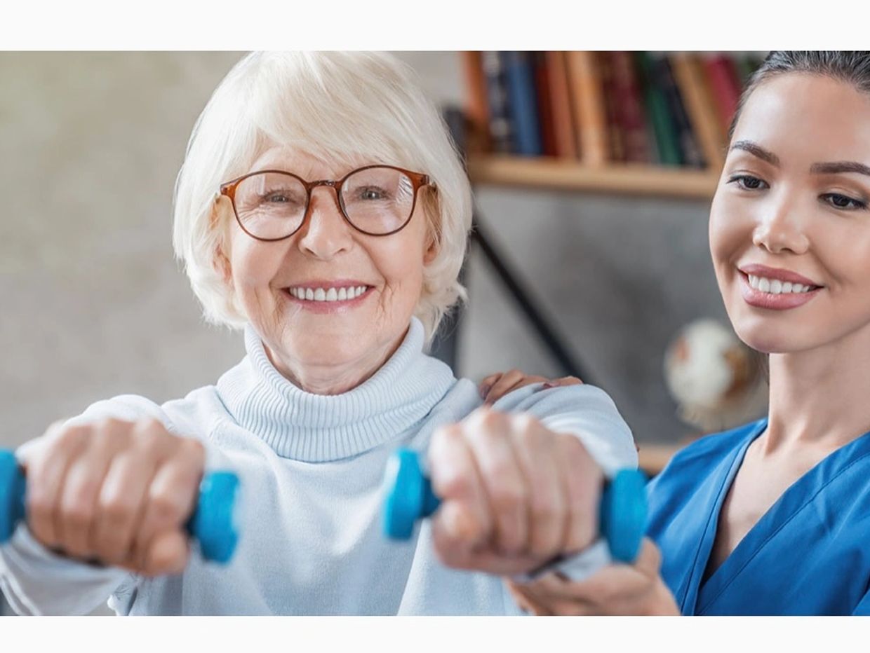 Physical therapist helping an elderly woman with strengthening exercises.
