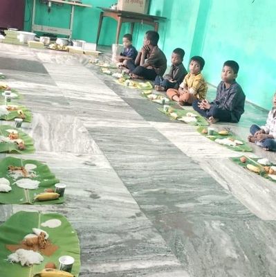 Children sitting on the floor having a meal served on banana leaves.