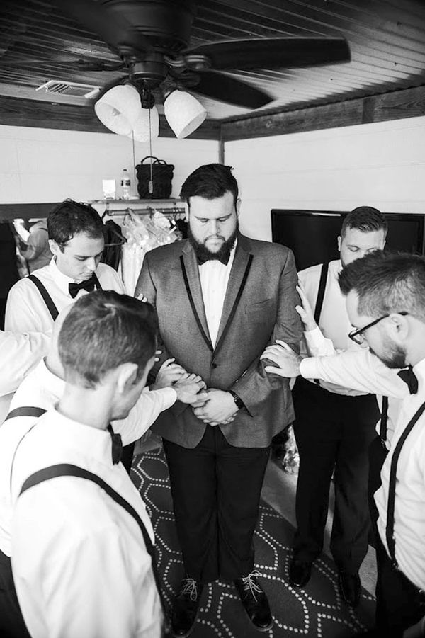 groom praying with his groomsmen before wedding ceremony