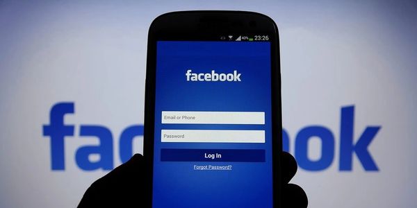 Smartphone showing Facebook login screen with blurred Facebook logo background.