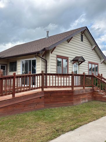 Off-white home with a wood front porch and ramp.