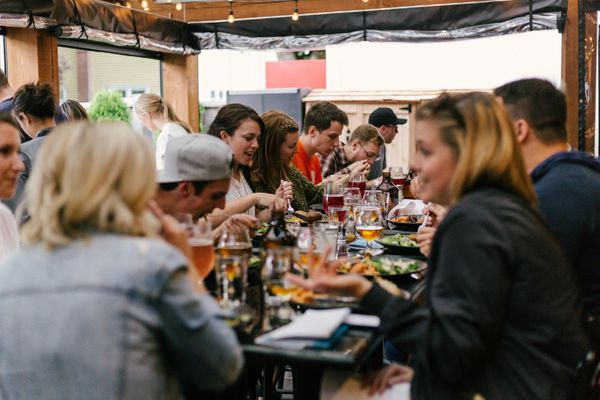 Group of friends enjoying a meal and drinks at an outdoor restaurant.
