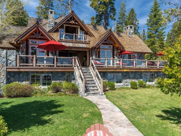 Rustic mountain house with stone and wood exterior surrounded by trees.