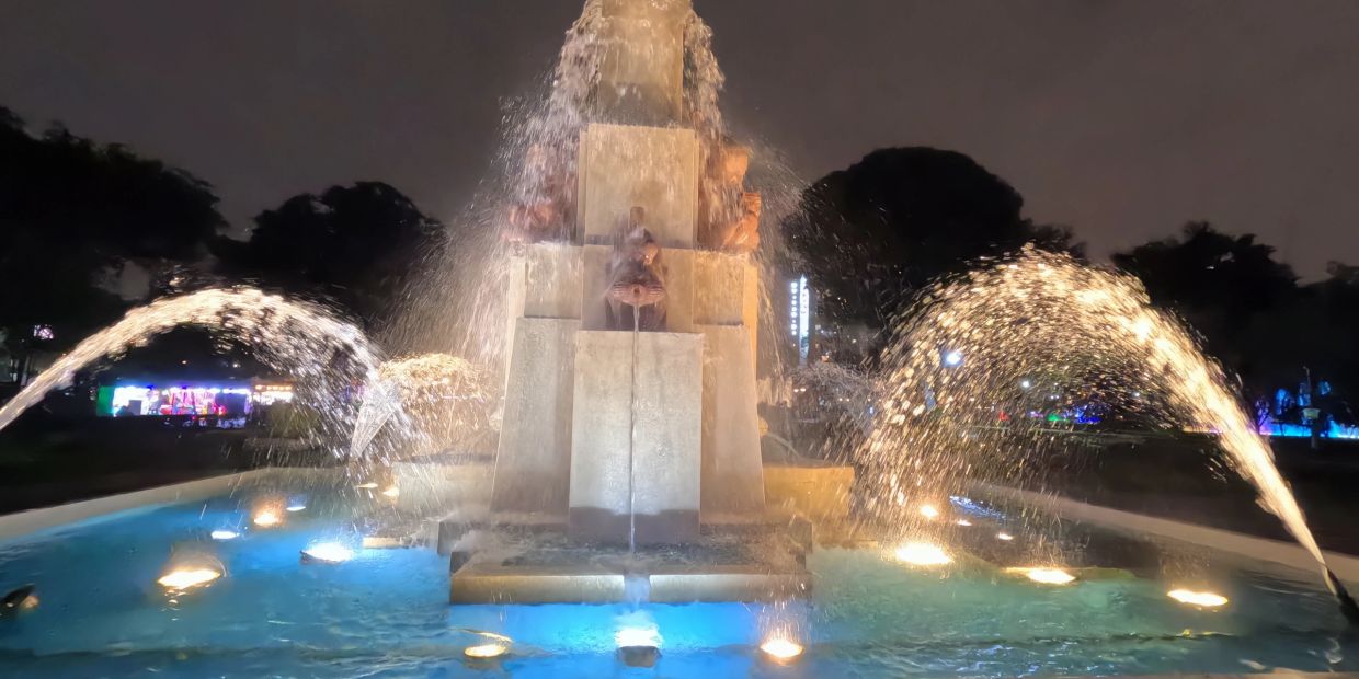 Illuminated fountain with water jets at night in a park.