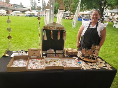 Woman selling bookmarks and jewelry crafts at outdoor market.