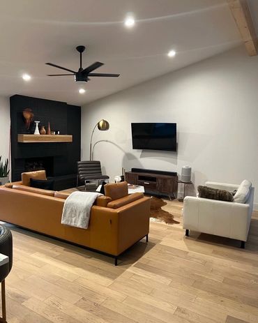 Modern living room with leather sofa, armchairs, and mounted TV.