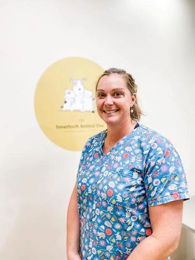 Smiling female veterinarian in colorful scrubs at animal clinic.