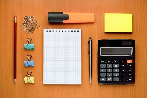 An organized desk setup featuring a pencil, paper clips, a notepad, a highlighter, sticky notes