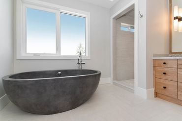 Modern bathroom with a sleek black freestanding bathtub and natural wood vanity.
