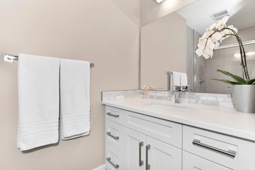 Modern bathroom with white towels and orchid on countertop.
