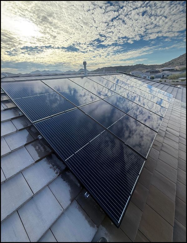 Solar panels on a rooftop under a cloudy sky.