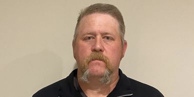 Portrait of a man with a distinctive mustache against a plain background.