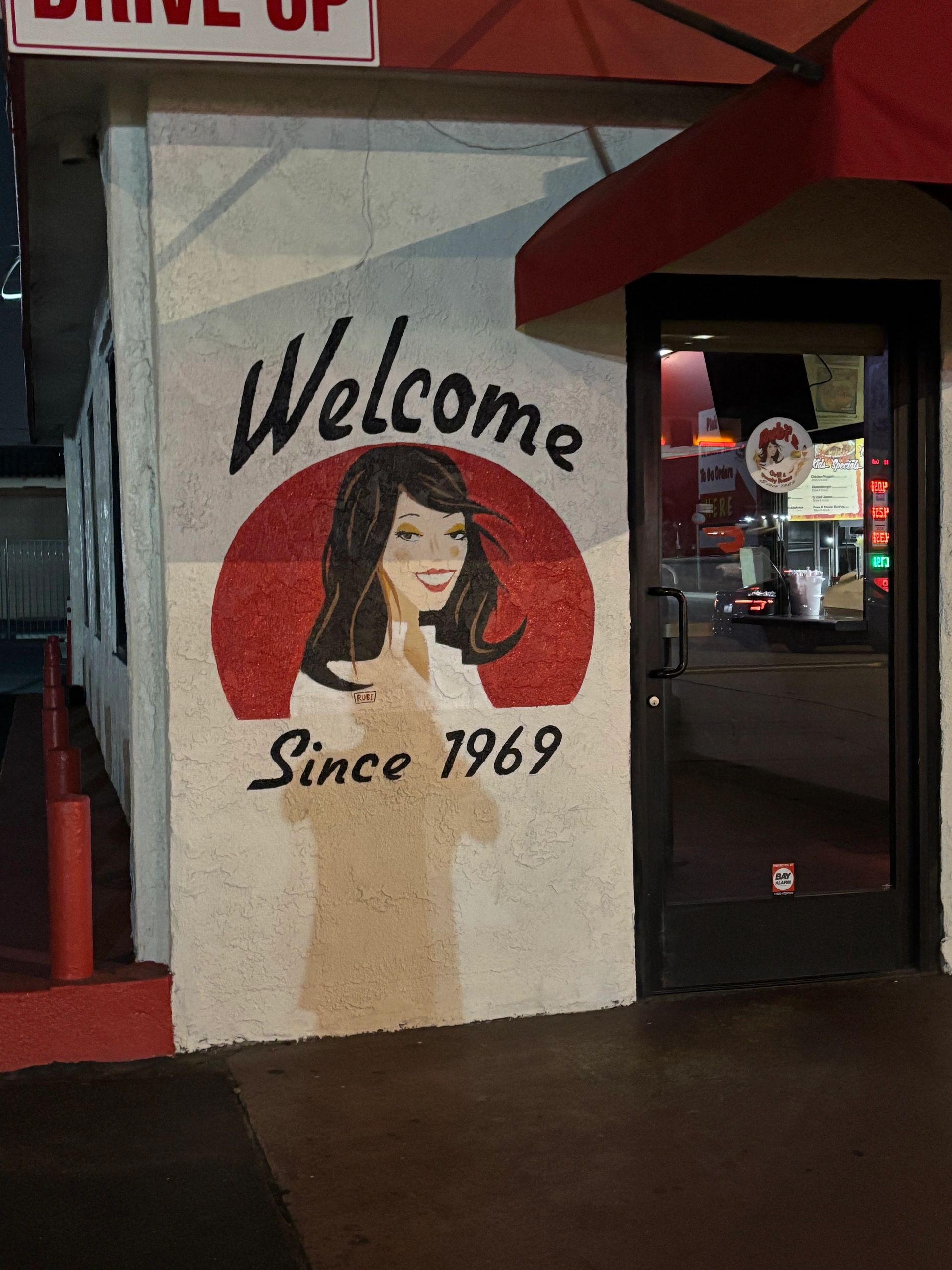Mural of a smiling woman with "Welcome Since 1969" text.