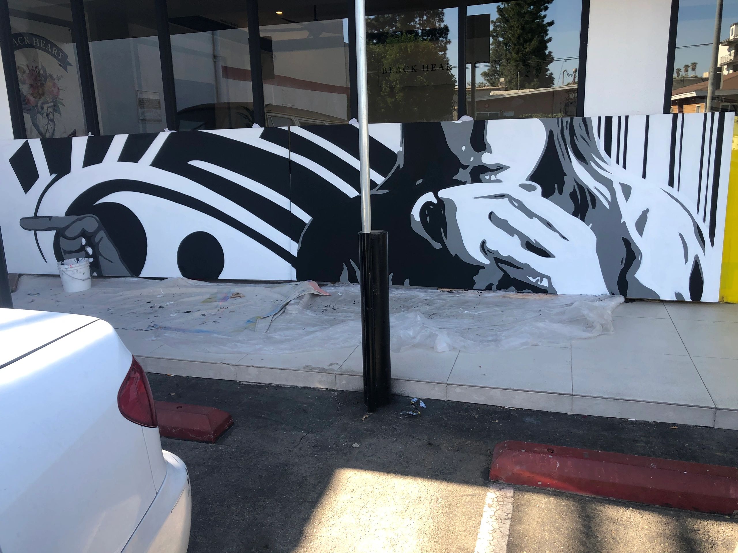 Black and white mural of a woman drinking from a cup.