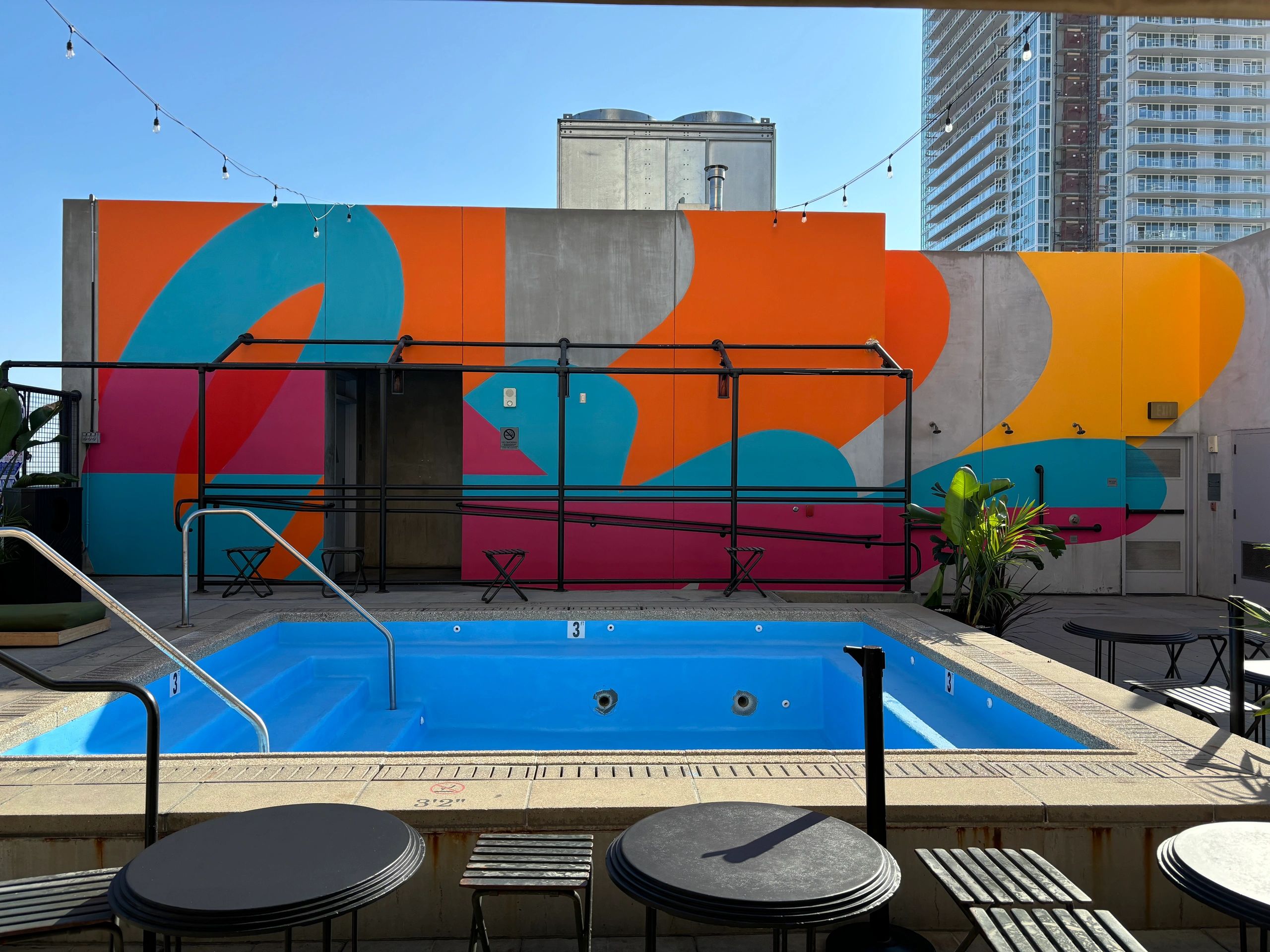 Empty blue pool with colorful mural in the background.