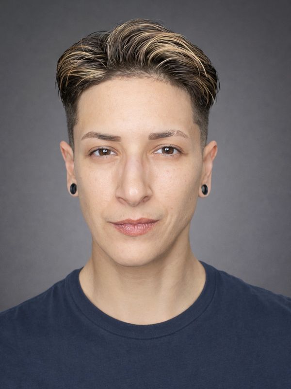 Portrait of a person with short, highlighted hair and dark earrings.
