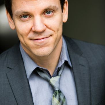 Man in a suit with a relaxed smile and loosened tie.